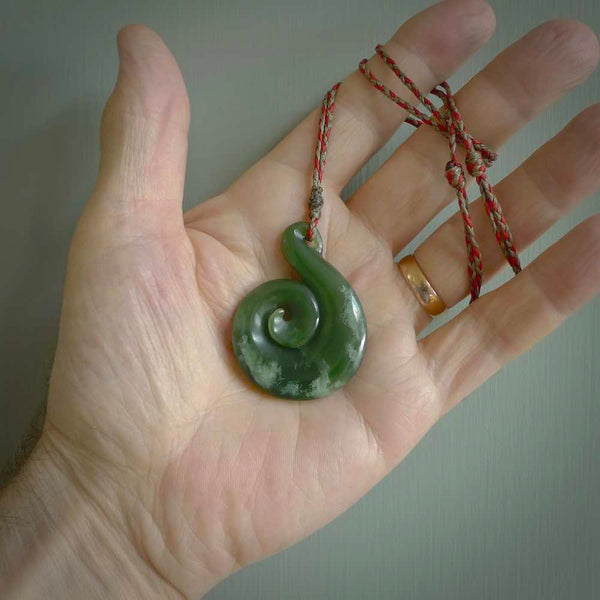 This pendant is a large sized and beautiful koru necklace carved from an orange and green piece of New Zealand Flower Jade. Ross Crump carved this piece for us so the workmanship is outstanding. Handmade in New Zealand, a beautiful piece of jade jewellery.