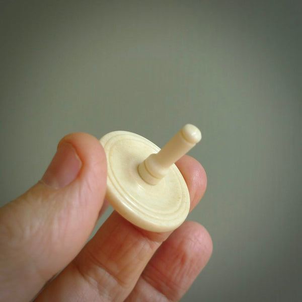 A traditional hand carved bone spinning top toy. This piece is made from bone and is a fully functioning toy that can be played with. Beautiful, contemporary art hand made by NZ Pacific.