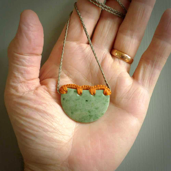 Hand carved Waimea pounamu disc pendant. These beautiful pieces have been carved for us by Raegan Bregmen and are quite beautiful. The soft green colours are lovely and are set off with a Khaki cord and Sunrise ridge binding.