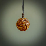 A hand carved and intricate koru pendant made for us by Yuri Terenyi. This is a beautiful little piece and is emblematic of the well known and loved Koru design. It is carved from bone in a hollowed, oval ball shape with decorative design carved into the koru. It is suspended from a Black cord with a wapiti brown floret and the necklace is adjustable.