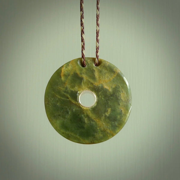 This picture shows beautiful flower jade disc pendant. This piece has a little sterling silver lined hole in the middle of the disc.