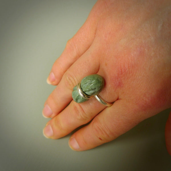 This is a handcrafted New Zealand Marsden jade squeezed ring with sterling silver. This is a solid little work of art. We ship this worldwide for free and are happy to answer any questions that you may have about these or other products on our website.