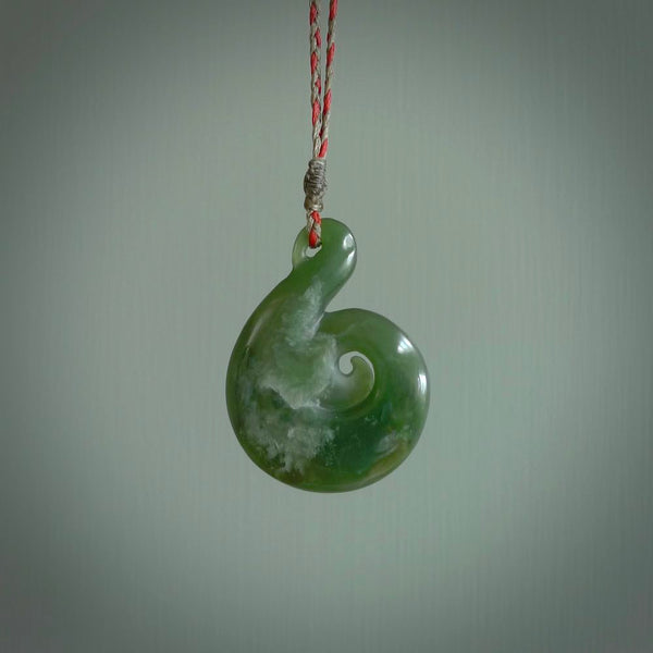 This pendant is a large sized and beautiful koru necklace carved from an orange and green piece of New Zealand Flower Jade. Ross Crump carved this piece for us so the workmanship is outstanding. Handmade in New Zealand, a beautiful piece of jade jewellery.