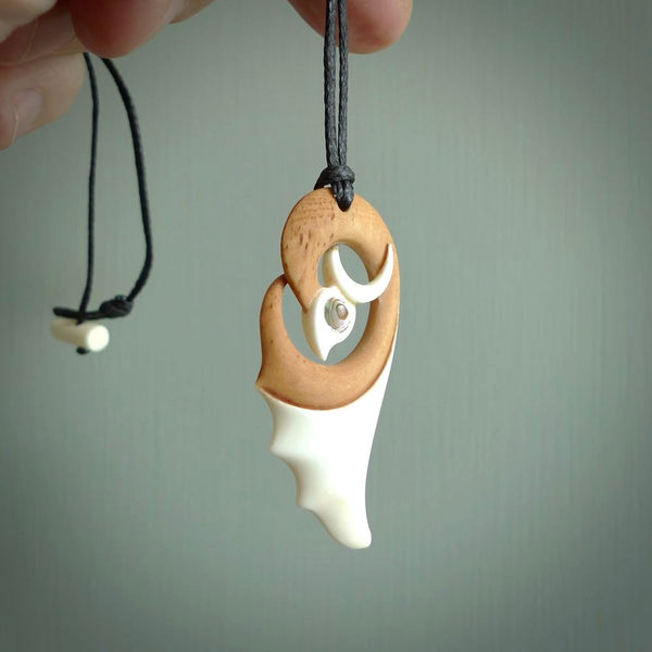 A hand carved bone contemporary bird pendant. The cord is a black colour and is a fixed length. A medium sized hand made contemporary necklace by New Zealand artist Kerry Thompson. Kerry has stained parts of the bone which really add to the dimension of this pendant. One off work of art to wear.