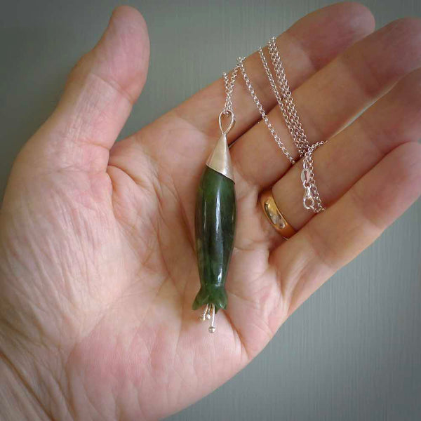 A photo of a harakeke, or flax flower, carved from a colourful piece of New Zealand flower jade. The cap and stamens are made from Sterling Silver and the cord is an Olive braid which is length adjustable.