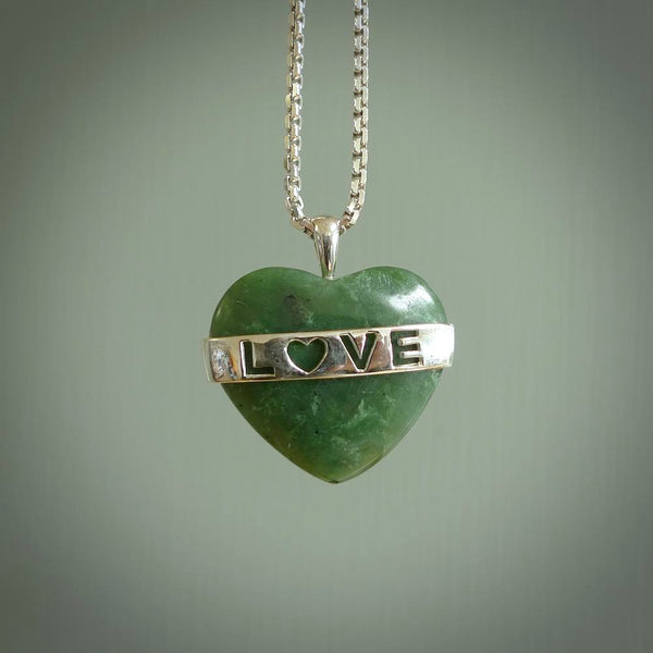 Hand crafted New Zealand jade love heart necklace. This piece has  a sterling silver love written across its' body. This necklace is provided with a sterling silver chain.