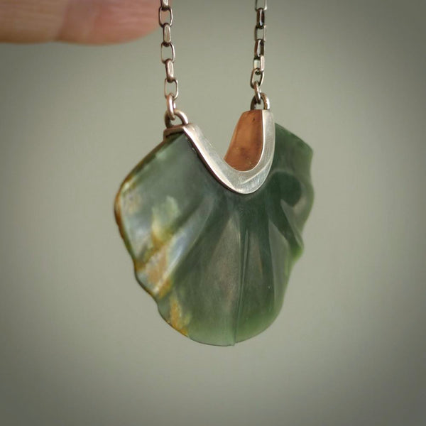 This is a very dark green fan design pendant that we has been carved here in New Zealand by Josey Coyle. It is carved from a piece of New Zealand Marsden flower Jade pounamu with Sterling Silver fittings and a sterling silver chain. A contemporary fan shaped pendant made to wear.