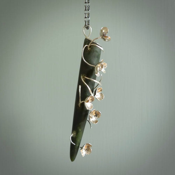 This picture shows a beautiful jade drop pendant with sterling silver flowers. This is a spectacular work of art and is a one off piece. Hand carved from New Zealand Jade with sterling silver flowers, replicating flowers in a vase.