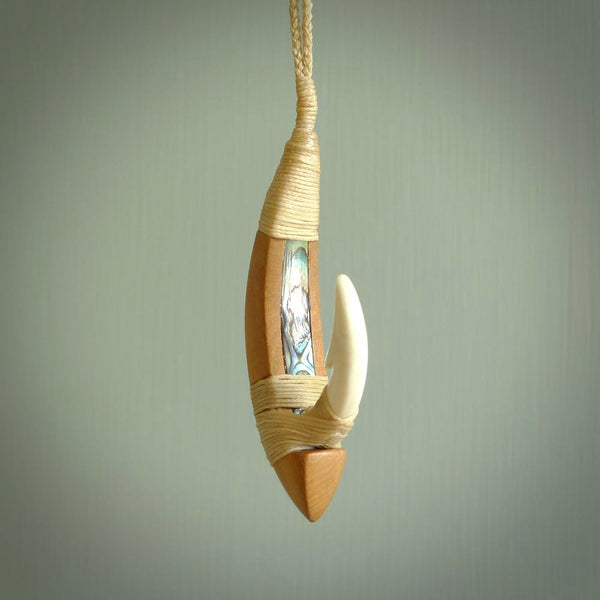 This picture shows a large matau, hook called a pā kahawai. It is carved from bone,  wood, and paua shell. One only, free shipping worldwide. Provided with an adjustable beige cord. Stunning work of Art to Wear by Andrew Doughty.