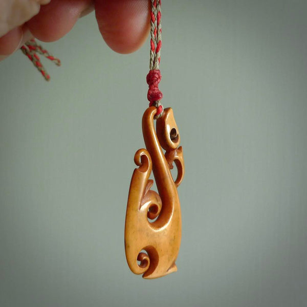 Natural stained cow bone manaia, hook with koru pendant. Hand carved by Yuri Terenyi in New Zealand. Maori design pendant for sale online. One only stained bone manaia, hook with koru necklace. Free delivery worldwide.