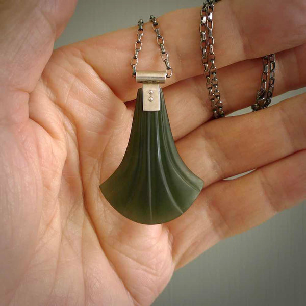 This is a very dark green shield style design pendant that has been carved here in New Zealand by Josey Coyle. It is carved from a piece of New Zealand Marsden Jade pounamu with Sterling Silver fittings and a sterling silver chain. A stunning contemporary necklace made to wear.