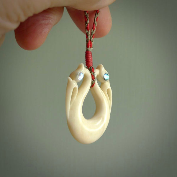 This is a unique double manaia, pekapeka, handcarved bone pendant from cow bone. The cord is Red and Khaki and is length adjustable. This is delivered to you with Express Courier. The eyes are made from Paua shell.