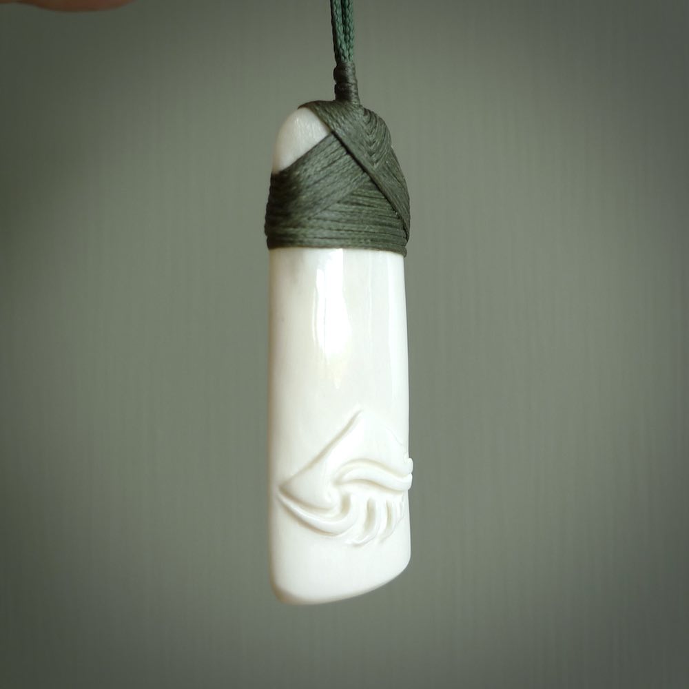 A hand carved bone toki with NZ Pacific logo engraving. Unique hand made jewellery from New Zealand Pacific.