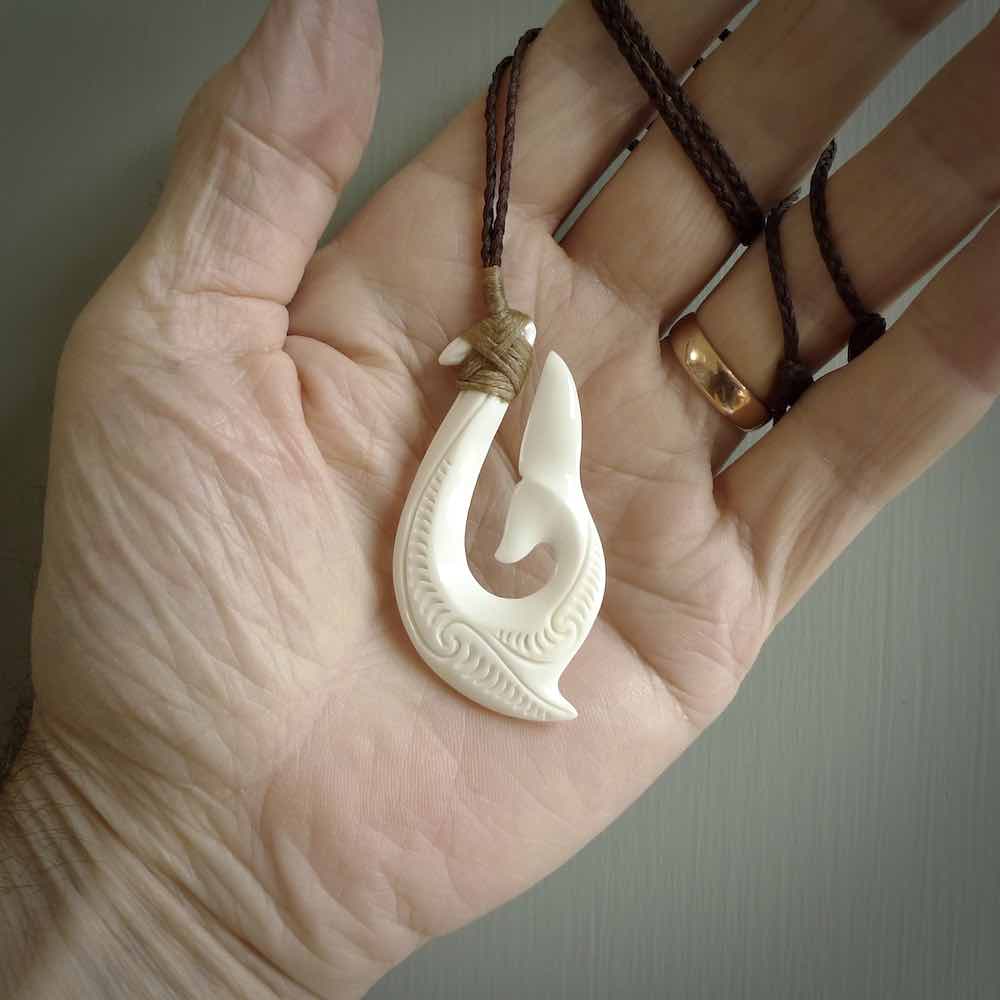 A handcarved hook pendant with a whaletail end. This is carved from bone and is detailed with a traditional Maori engraved design. We will ship this piece to you anywhere in the world and the price for shipping is included in the price. Unique bone jewellery for sale online at www.nzpacific.com