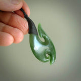 This is a beautiful flower jade hook with a little decorative koru carved into the bottom. It is a chunky piece but beautifully balanced so doesn't look heavy. The cord is a Black colour and the binding on the top is also black.