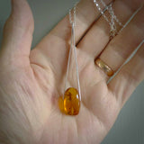 A hand made Burmite amber pendant. We have clasped this piece of amber in a pair of handmade Sterling Silver tweezers designed like jewellers tweezers. The amber is beautifully displayed and has a fly-like insect embedded in the resin.