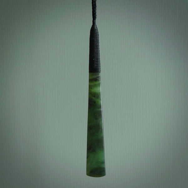 This photo shows a large jade drop shaped pendant. It a a lovely two-one green jade. Majority of this piece is a dark green colour with a semi-translucent top of the drop. The cord is black and is adjustable in length. Hand carved by Darren Hill.