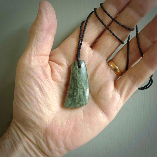 A hand carved curved contemporary drop pendant. This is a piece of genuine jade jewellery, hand carved by Raegan Bregmen. He has used rare New Zealand jade and has utilised his experience and carving skill to highlight the natural beauty of the stone. Delivered worldwide, postage is included in the price.