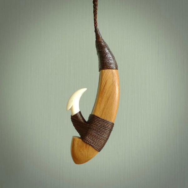 This picture shows a large matau, hook called a pā kahawai. It is carved from bone,  wood, and paua shell. One only, free shipping worldwide. Provided with an adjustable brown cord. Stunning work of Art to Wear by Andrew Doughty.