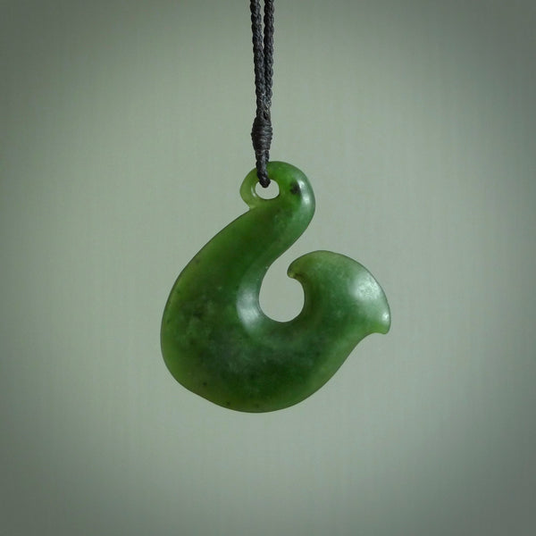 This picture shows a jade hook pendant, also called a hei-matau, carved for us in New Zealand jade. The jade is a wonderful pale mint green pounamu. This is a rare jade loved and valued for its distinctive colour. The carver is Ric Moor - and this is a beautiful example of his work. The cord is a four-plait, adjustable black coloured necklace.