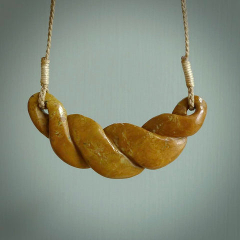 This piece is a large, contemporary, twist pendant. It was carved for us by Alex Sands from a lovely orange piece of New Zealand Flower jade. It is suspended on a tan coloured braided cord that is length adjustable.