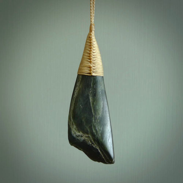 This photo shows a large jade drop shaped pendant. It a a lovely deep green jade. The cord is a four plait beige and is adjustable in length. One only large, contemporary drop necklace from Jade, by Ric Moor.