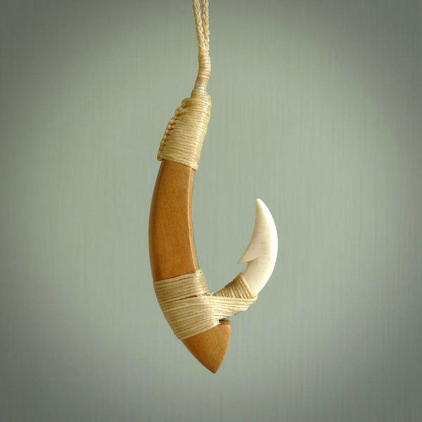 This picture shows a large matau, hook called a pā kahawai. It is carved from bone,  wood, and paua shell. One only, free shipping worldwide. Provided with an adjustable beige cord. Stunning work of Art to Wear by Andrew Doughty.