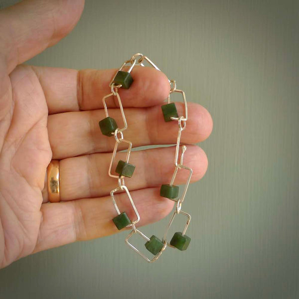 This bracelet is handmade from New Zealand Jade and sterling silver. It has a delicate cube of pounamu within each link of Sterling Silver chain and the Jade moves within each chain link.