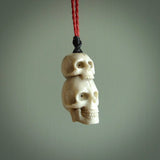 This photo shows a double skull pendant hand carved in deer antler. It is provided with a plaited cord necklace which is length adjustable.