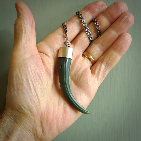 This picture shows a hand carved Inanga jade huia beak pendant with sterling silver cap and chain. The jade is a very dark green. It is suspended from a sterling silver clasp and we supply a sterling silver chain. Delivery is free worldwide.