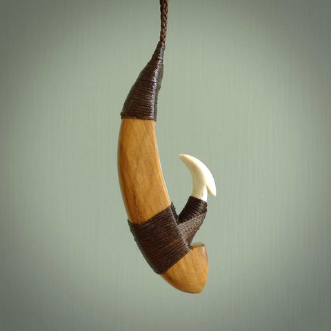This picture shows a large matau, hook called a pā kahawai. It is carved from bone,  wood, and paua shell. One only, free shipping worldwide. Provided with an adjustable brown cord. Stunning work of Art to Wear by Andrew Doughty.