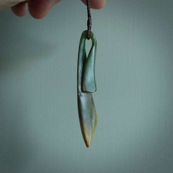 This piece is a large, contemporary, drop pendant. It was carved for us by Ric Moor from a lovely green piece of New Zealand flower jade with orange colours at the base. It is suspended on a beige coloured braided cord that is length adjustable.
