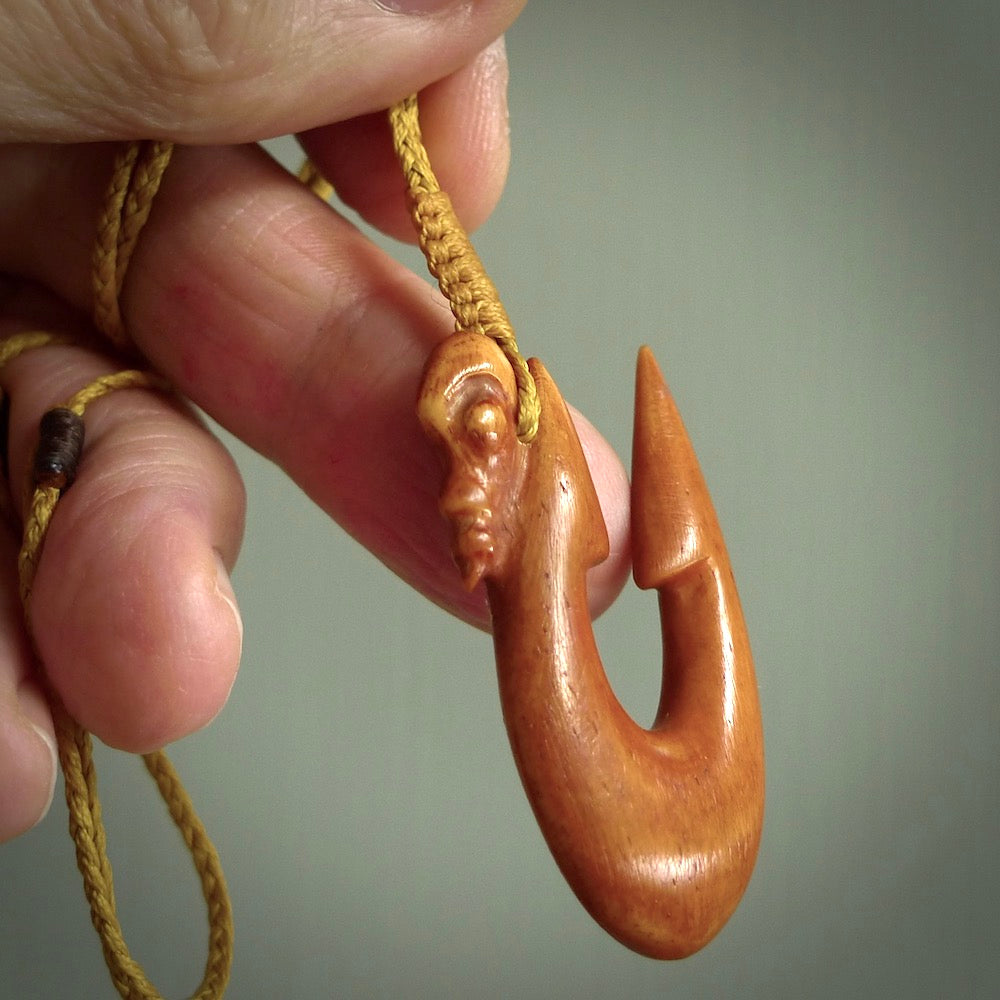 HAND CARVED NATURAL BONE HOOK WITH MANAIA FACE PENDANT. BONE HOOK