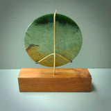 A spectacular, flower jade disc sculpture. Hand carved in New Zealand from stunning Flower Jade. This is a beautiful plate-sized disc sculpture carved in a lovely bright green jade. It is presented with a wooden display stand. A beautiful sculptural piece hand carved in New Zealand.