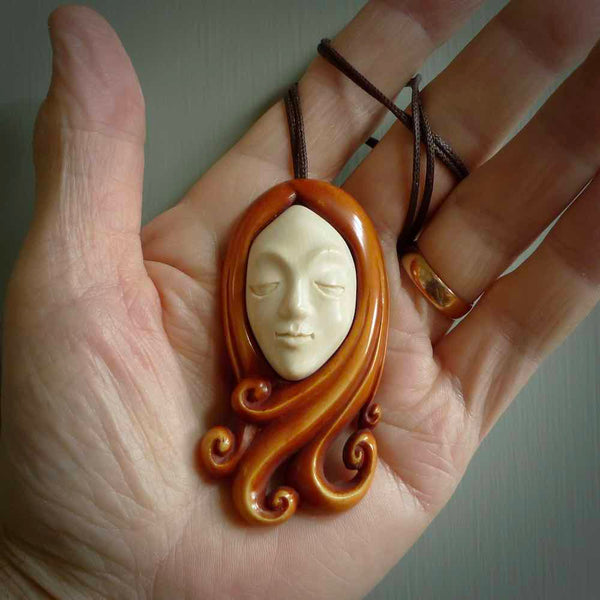 This is a hand carved bone contemporary female pendant. Yuri Terenyi has carved this from Stained Bone with Woolly Mammoth Tusk and Paua Shell inlay on the back of the pendant. It is a delightful, large and artistic piece of jewellery. One only necklace. The necklace is provided on an adjustable cord in a hand made, custom, wooden box.