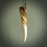 Hand carved Deer Antler Spring of Life pendant with Paua shell cap. This is a longish piece carved from the tip of a deer antler tine. The skin of the antler has been worked into the design so it is an organic design that shows its heritage. Carved for NZ Pacific by Fumio Noguchi.