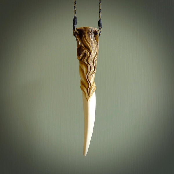 Hand carved Deer Antler Spring of Life pendant with Paua shell cap. This is a longish piece carved from the tip of a deer antler tine. The skin of the antler has been worked into the design so it is an organic design that shows its heritage. Carved for NZ Pacific by Fumio Noguchi.