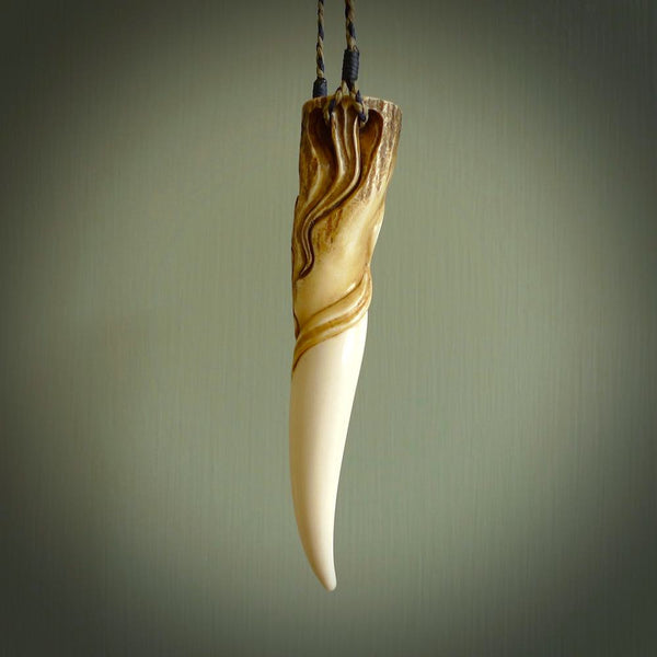 Hand carved Deer Antler Spring of Life pendant with Paua shell cap. This is a longish piece carved from the tip of a deer antler tine. The skin of the antler has been worked into the design so it is an organic design that shows its heritage. Carved for NZ Pacific by Fumio Noguchi.