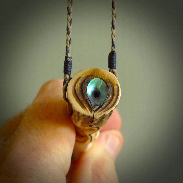 Hand carved Deer Antler Spring of Life pendant with Paua shell cap. This is a longish piece carved from the tip of a deer antler tine. The skin of the antler has been worked into the design so it is an organic design that shows its heritage. Carved for NZ Pacific by Fumio Noguchi.