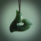 This photo shows a perfectly New Zealand jade hook pendant. It is hand carved from a deep green piece of New Zealand jade and is suspended on a brown four plait cord that is length adjustable.