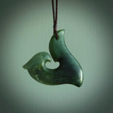 This photo shows a perfectly New Zealand jade hook pendant. It is hand carved from a deep green piece of New Zealand jade and is suspended on a brown four plait cord that is length adjustable.
