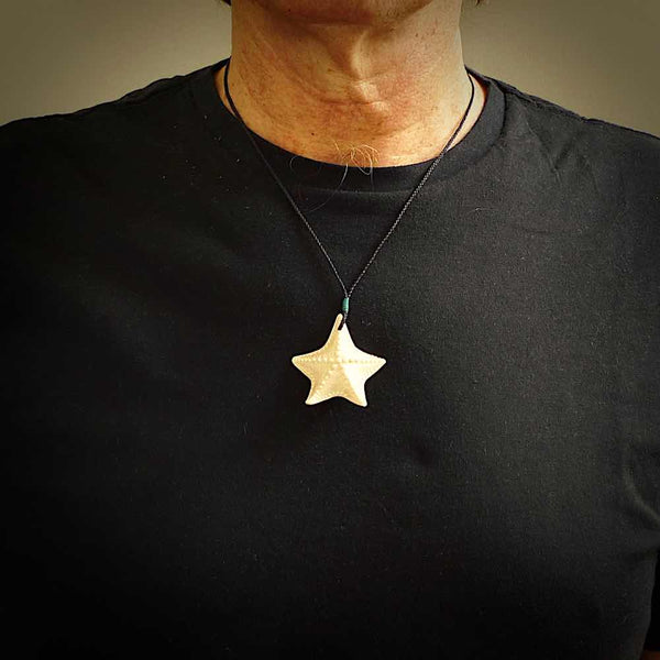 Hand carved bone starfish pendant shown worn. Ocean themed pendants carved by NZ Pacific. Moana pendants for sale online.