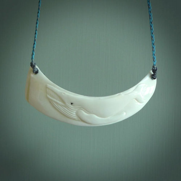 This photo shows a pendant we carved from boars tusk. It is a Blue Whale carved lengthwise into the tusk. This piece is suspended from a hand plaited necklace cord in Blue and Grey. This pendant is 100% hand made.