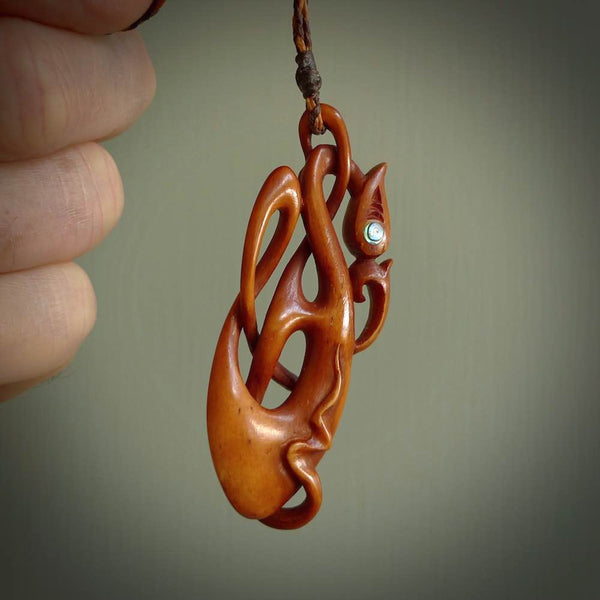 A one off beautiful piece of carved art. We have called this Enigma, it was hand carved for us by Yuri Terenyi and is a manaia with twist design pendant. This is a wonderful ethnic bone pendant designed to be worn. It has been stained by a homemade tea dye in a bright gingery brown colour and we have hand plaited an adjustable cord in khaki, ice white and ginger nut colours.
